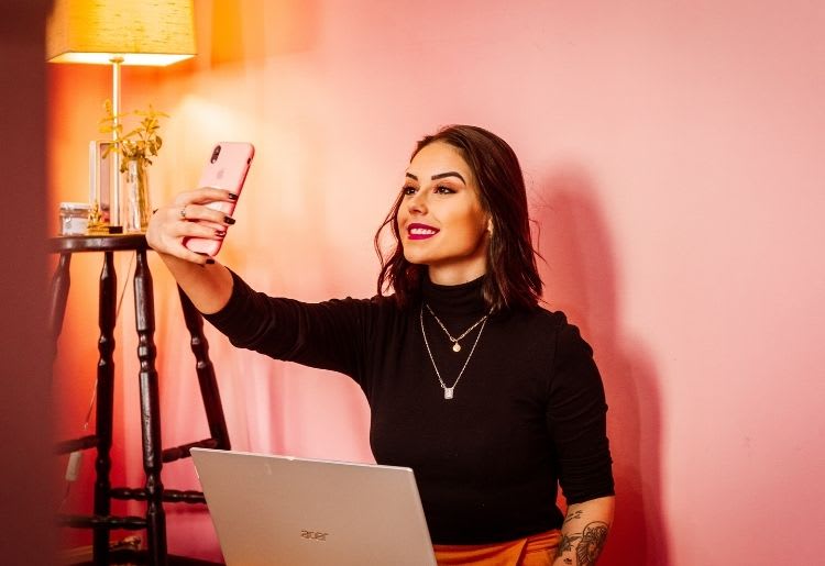 A beautiful young woman takes a selfie on her phone for her dating profile